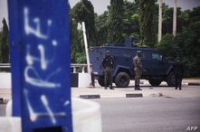 Policemen guard the road to the Aso Villa, official residence of the President of Nigeria, during clashes between members of…