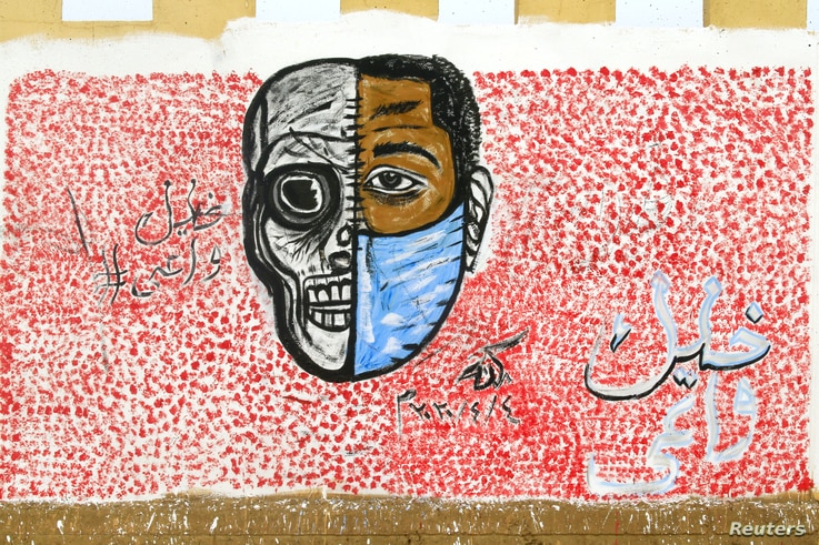A graffiti depicting the importance of face masks, part of a COVID-19 awareness-raising campaign, is pictured with the arabic…