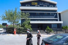 People walk past the Nalia Radio and Television (NRT) building in Sulaimaniyah city, in the Kurdish autonomous region of…
