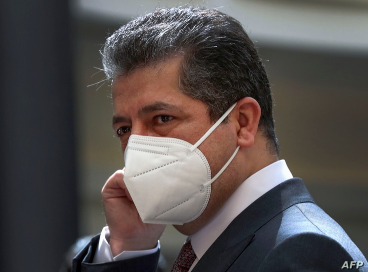 Prime Minister of the Regional Government of Iraqi Kurdistan Masrour Barzani adjusts his protective mask as he waits for the…