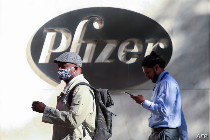People walk by the Pfizer world headquarters in New York on November 9, 2020. - Pfizer stock surged higher on November 9, 2020…