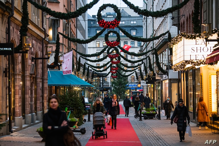People walk past shops under Christmas decorations in Stockholm on December 3, 2020, during the novel coronavirus COVID-19…