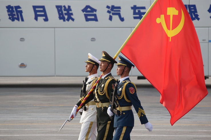 Soldiers of People's Liberation Army (PLA) march in formation with a Chinese Communist Party flag during a rehearsal before…