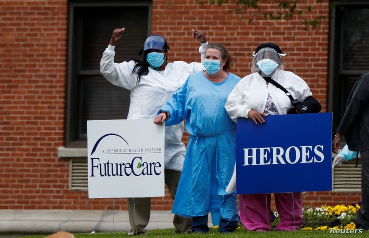 FILE - Medical workers pose for photos taken by coworkers as they stand with signs saying