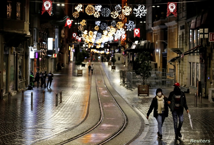FILE - Couple walks along Istiklal Street at the popular touristic neighbourhood of Beyoglu after a partial weekend curfew started during the COVID-19 outbreak in Istanbul, Turkey, Nov. 21, 2020.