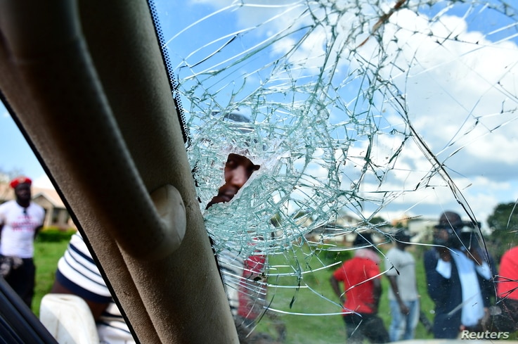 A man peers through the shattered windscreen of the car of Ugandan pop star and presidential candidate Robert Kyagulanyi, also…