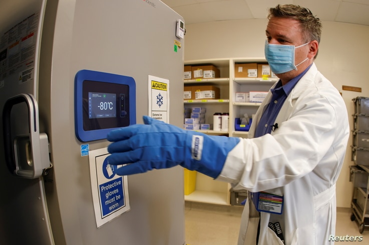 Pharmacy supervisor Kevin Weissman uses a thick glove as he opens the door of a special freezer that will hold the Pfizer…