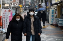 A couple wearing masks walks on a street amid the coronavirus disease (COVID-19) pandemic in Seoul, South Korea, December 13,…