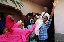 Muhammed Bello, a rescued student, is carried by his father as his relatives celebrate after he retuned home in Kankara,…