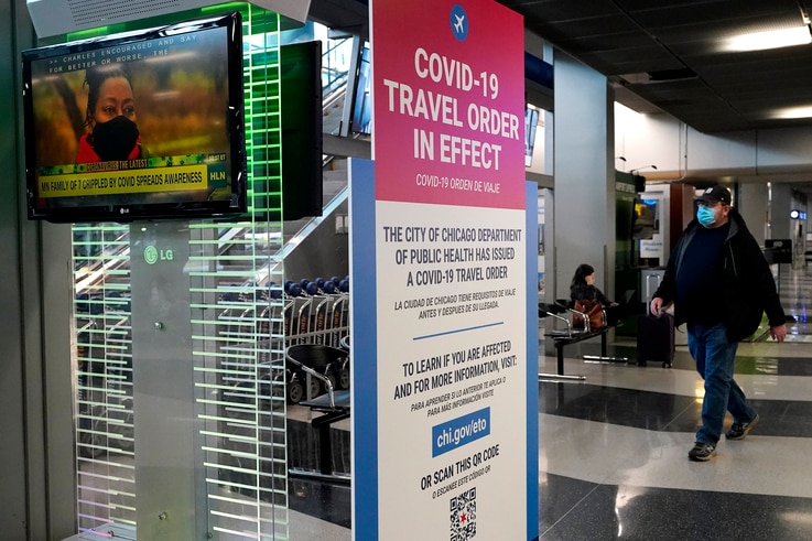 A traveler walks through Terminal 3 as a COVID-19 travel order sign is displayed at O'Hare International Airport in Chicago,…