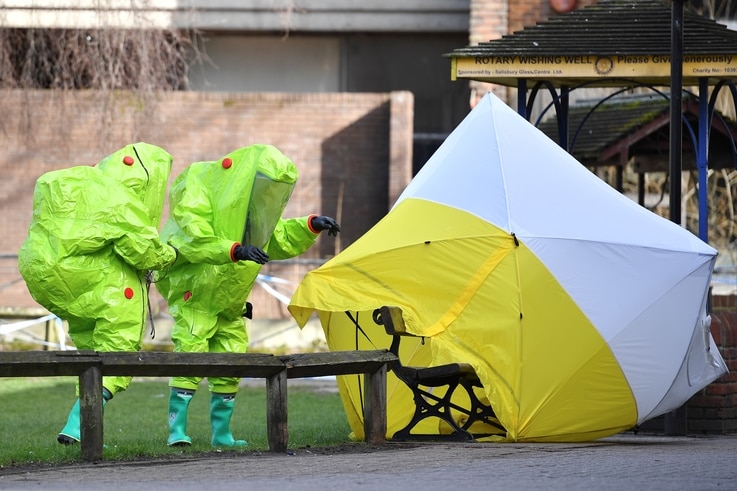 Des membres des services d'urgence en costume de protection encapsulé réapposent la tente sur le banc où l'espion russe Sergei Skripal et sa fille Yulia ont été retrouvés dans un état critique à Salisbury, Angleterre, 8 mars 2018.
