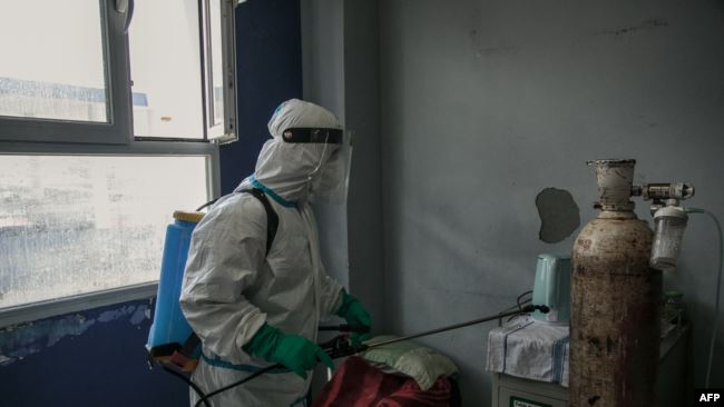 MADAGASCAR – health worker disinfects a room at the Andohatapenaka University Hospital.