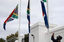 A policeman adjusts South African flags to half-mast outside parliament in Cape Town, South Africa, Wednesday, Nov. 25, 2020…