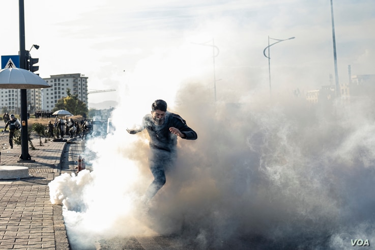 A protester runs through teargas as Kurdish security forces approach during anti-government demonstrations in the Iraqi Kurdistan city, Sulaymaniyah on Dec. 11, 2020. (Rebaz Majeed/VOA)