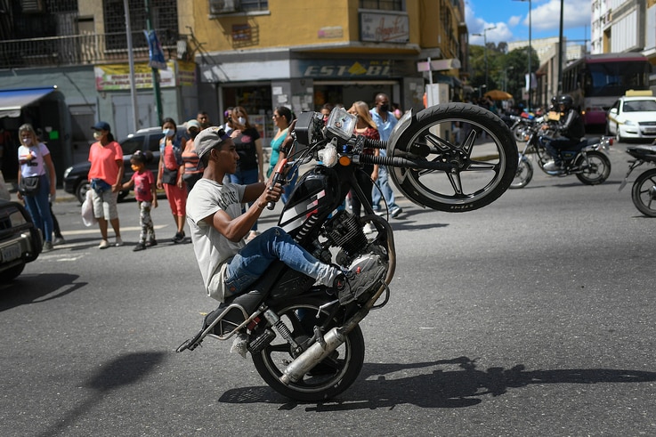 A supporter of President Nicolas Maduro performs a wheelie on his motorbike during a rally during on the same day the…
