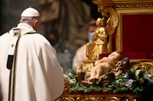 Pope Francis stands in front of a statue of Baby Jesus as he celebrates Mass on Christmas eve, at St. Peter's basilica at the…