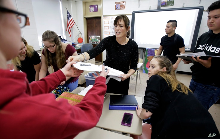 FILE - High school teacher Natalie O'Brien, center, hands out papers during a civics class in North Smithfield, R.I.
