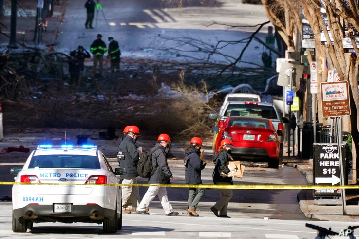 Investigators walk near the scene of an explosion Saturday, Dec. 26, 2020, in Nashville, Tenn. The explosion that shook the…