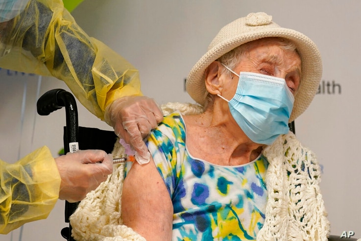 Registered nurse Cynthia Banada, left, administers the Moderna COVID-19 vaccine to Luz Collazo, 103, at Miami Jewish Health, a…