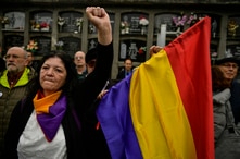 FILE - A woman holds up her left fist beside to a Spanish Republican flag during a tribute 46 unidentified people killed during the Spanish Civil War, at San Jose cemetery, Pamplona, northern Spain, April 1, 2019.