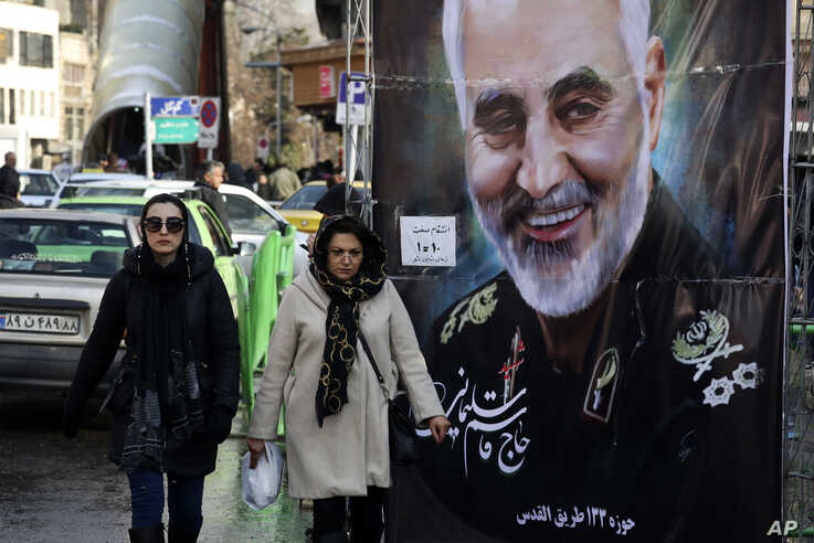 Women walk past a banner of Iranian Revolutionary Guard Gen. Qassem Soleimani, who was killed in Iraq in a U.S. drone attack on…