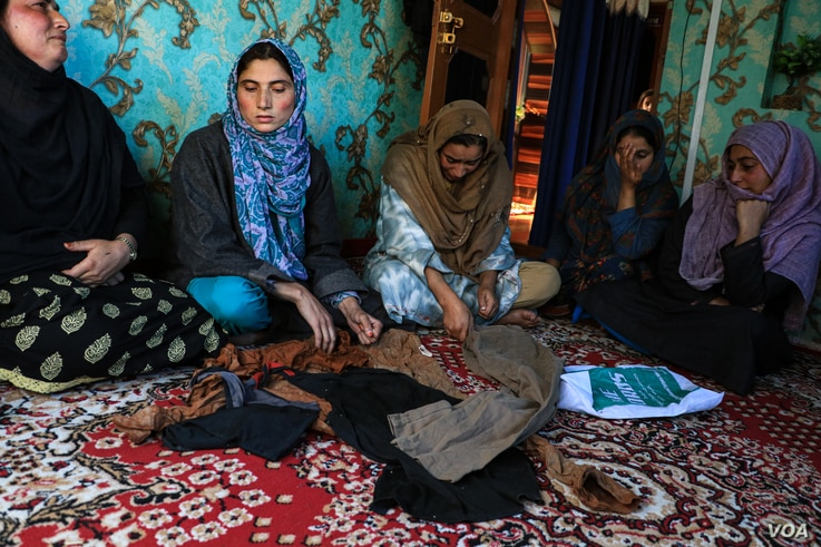 Family members of an Indian soldier, Shakir Manzoor, displaying his clothes after they were found in an orchid by his father in Shopian district of Indian administered Kashmir. (UbaidUllah Wani/VOA)