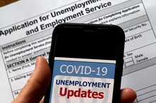 In this illustration photo taken May 08, 2020, a COVID-19 Unemployment Assistance Updates logo is displayed on a smartphone against the backdrop of an application for unemployment benefits, in Arlington, Virginia.