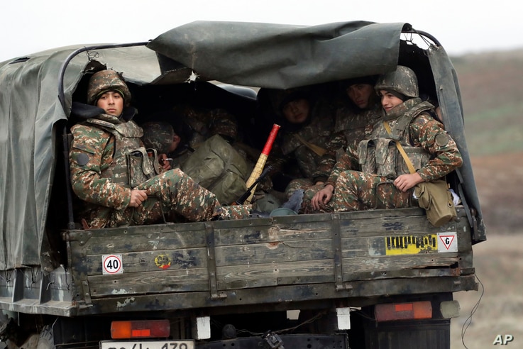 Ethnic Armenian soldiers sit in a military truck on a road during the withdrawal of troops from the separatist region of Nagorno-Karabakh, Nov. 19, 2020.