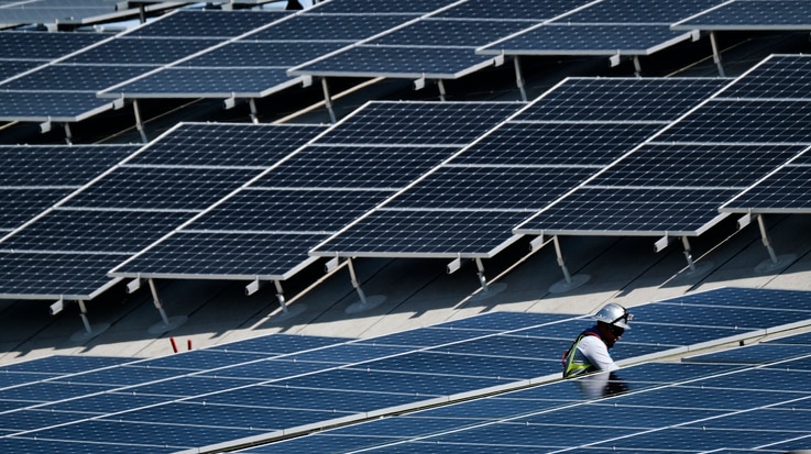 FILE - A worker installs solar panels on a roof at Van Nuys Airport in Los Angeles, California, Aug. 8, 2019.