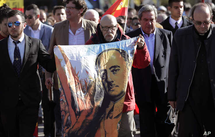 A man holds a depiction of the late Spanish dictator Gen. Francisco Franco as people gather outside Mingorrubio's cemetery, on the outskirts of Madrid, Spain, Oct. 24, 2019.