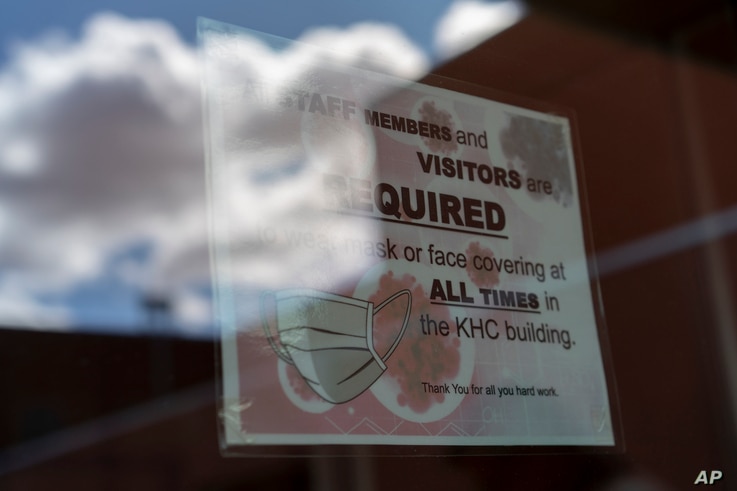 FILE - A sign on a door warns people to wear face coverings, at the Kayenta Health Center on the Navajo reservation in Kayenta, Arizona, April 18, 2020. Across the nation, Native American tribes are working to protect their oldest members from COVID.