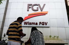 A couple talks outside FGV Holdings Berhad, one of Malaysia's largest palm oil companies, in Kuala Lumpur, Thursday, Oct. 1,…