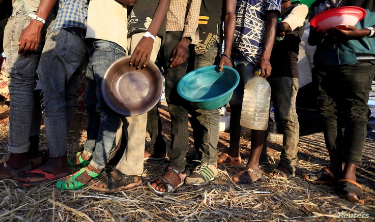 Ethiopian refugees who fled the country's restive Tigray region queue to receive food aid at the Um-Rakoba camp in Al-Qadarif state, in Sudan, Dec. 11, 2020.