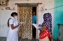 Health workers collect personal data from a man as they prepare a list during a door-to-door survey on the outskirts of Ahmedabad