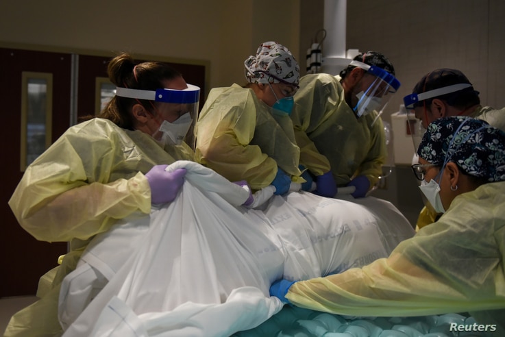 Healthcare personnel rotate a patient who is on a ventilator at a hospital in Hutchinson, Kansas, Nov. 20, 2020.