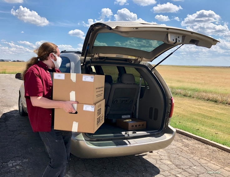 A volunteer with the High Plains Food Bank in Amarillo, Texas puts boxes of food into a car to bring to people in a rural community. (High Plains Food Bank)