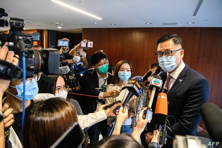 Pro-democracy lawmaker Lam Cheuk-ting (R) speaks to reporters after displaying two banners outside the main chamber of the…