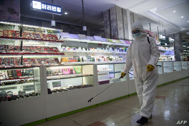 A health worker sprays disinfectant inside the Pyongyang Department Store No. 1 prior to opening for business, in Pyongyang on…
