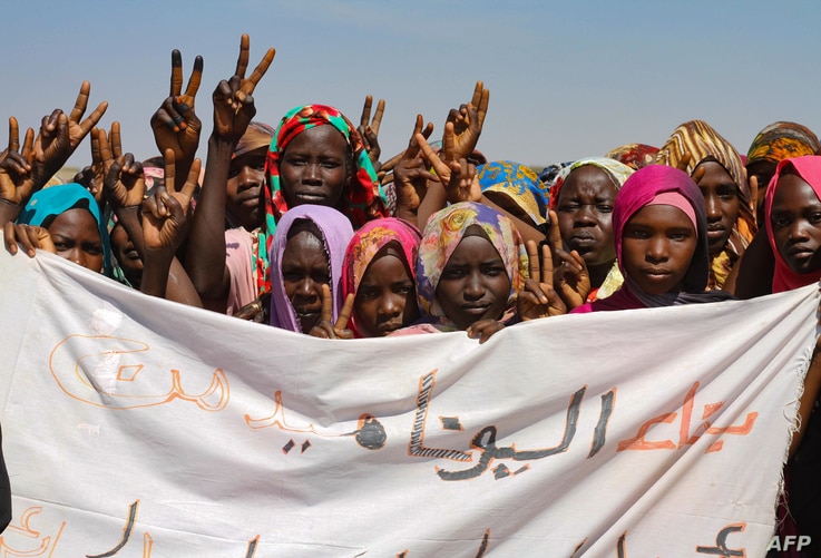 Sudanese internally displaced people hold a banner as they stage a sit in to protest against the end of the mandate of the…