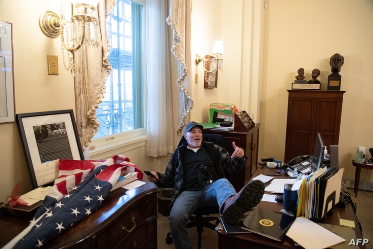 Richard Barnett, a supporter of US President Donald Trump sits inside the office of US Speaker of the House Nancy Pelosi as he…