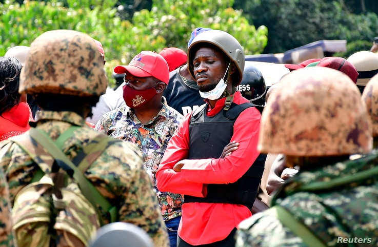 Ugandan opposition presidential candidate Robert Kyagulanyi, also known as Bobi Wine (C), is escorted by policemen during his…