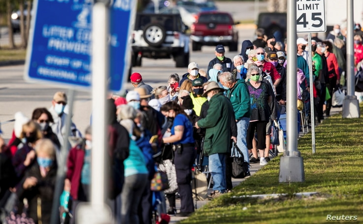 Hundreds wait in line at Lakes Park Regional Library to recieve the COVID-19 vaccine in Fort Myers, Florida, U.S. December 30,…