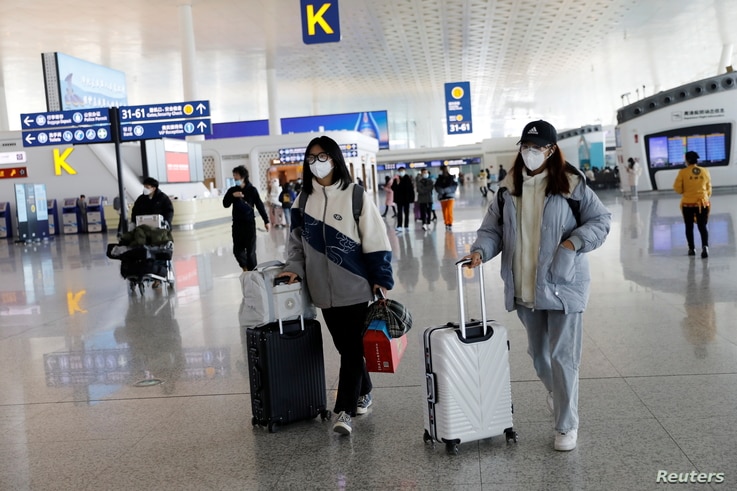 Travellers walk with their luggage at Wuhan Tianhe International Airport following the coronavirus disease (COVID-19) outbreak.