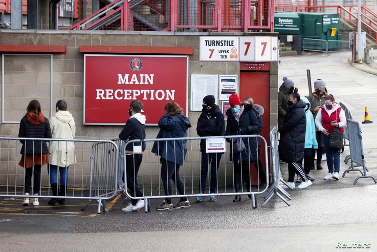 People queue for COVID-19 testing at a mass screening center at Charlton Athletic Football Club, London.