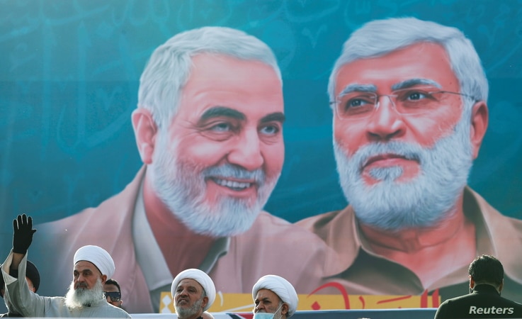 Iraqi clerics look on as they stand near a banner depicting senior Iranian military commander General Qassem Soleimani and…