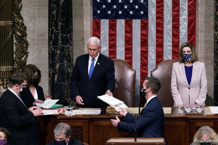 U.S. Vice President Mike Pence hands the West Virginia certification to staff as Speaker of the House Nancy Pelosi looks on.