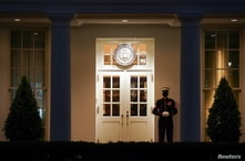 A U.S. Marine stands guard at the entrance to the West Wing as nighttime descends upon the White House in Washington.