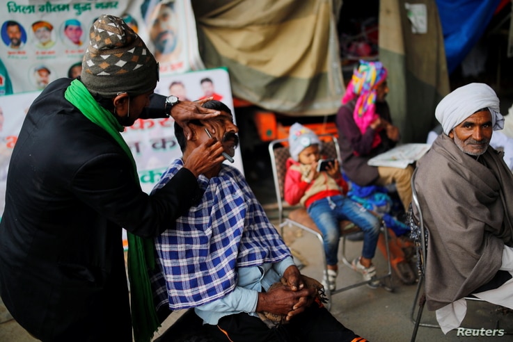 A farmer gets a shave from a barber at the site of a protest against new farm laws, at the Delhi-Uttar Pradesh border in Ghaziabad, India, Jan. 12, 2021.