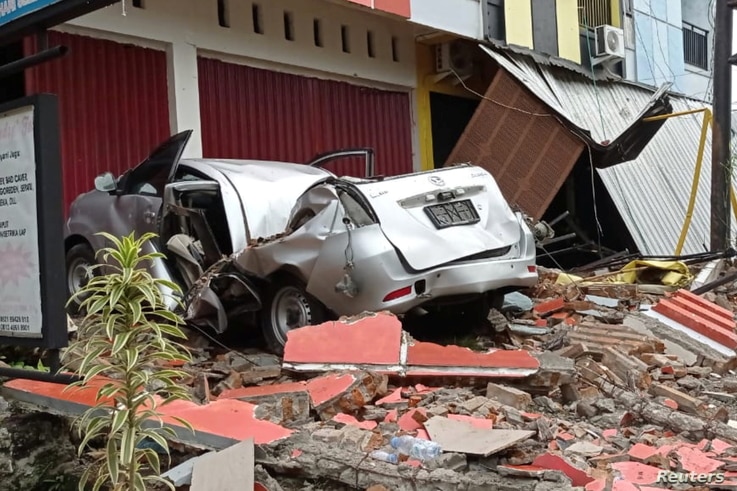 A damaged car and buildings are seen following an earthquake in Mamuju, West Sulawesi province, Indonesia, January 15, 2021 in…