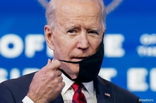 U.S. President-elect Joe Biden adjusts his face mask as he speaks about his plan to administer coronavirus disease (COVID-19)…